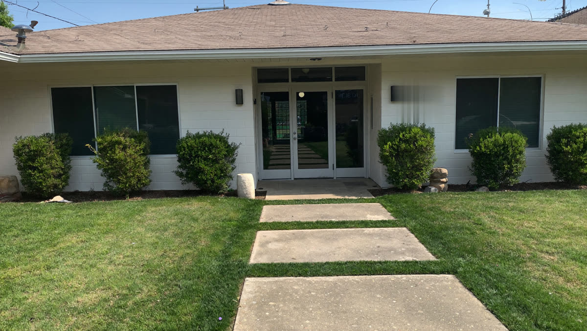 Well-maintained commercial building entrance with trimmed shrubs and clean walkway